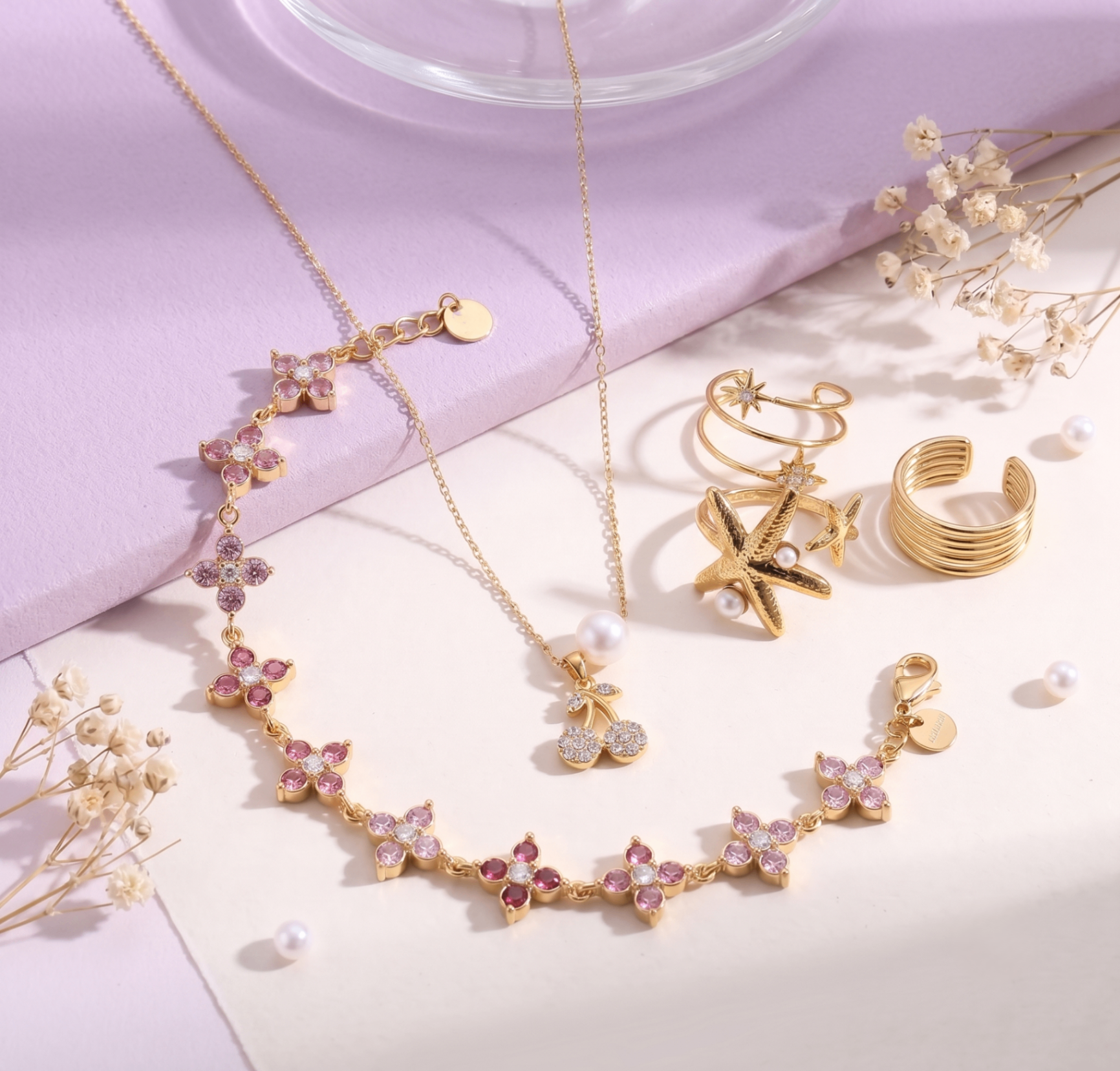 Bijoux Cherry Bijoux en plaqué or 14K et pierres roses sur fond lilas